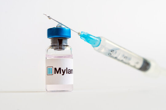 Vials of liquid on a white table and the logo of a large pharmaceutical company.