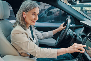 Mature beautiful woman in smart casual wear using global positioning system while driving car