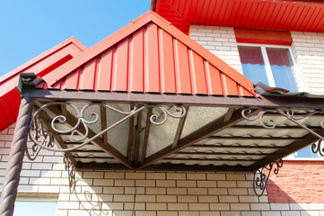 close-up - red roof of the house, beige brick walls, forging under the roof
