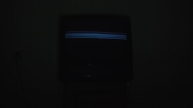 Old tv screen shows broken analog signal in dark hotel room. Concept vintage and retro technology.