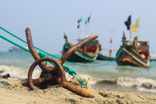 A fishing boat anchored by the beach in St. Martin's Island, Bangladesh. Fishing boat rusty traditional anchor on a beach by the sea. Rusty anchor wet beach sand and wave.