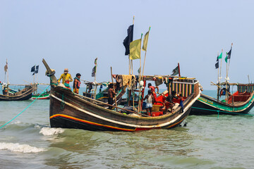 Fishermen and their colorful fishing boats. The fishing industry in Bangladesh. Bangladeshi traditional fishing boat on St. Martin's Island. Fisherman preparing boat for sailing into the ocean.