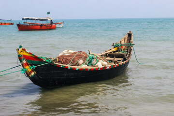 Fototapeta na wymiar Bangladeshi traditional fishing boat on St. Martin's Island. Fisherman preparing boat for sailing into the ocean. Colorful fishing boats.