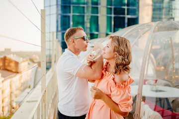 man and woman drink champagne on bruderschaft in a rooftop cafe. 