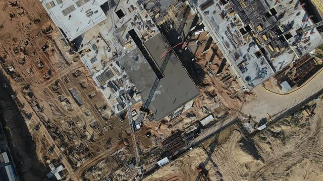 Construction site. The concrete frame of the building is being erected. Construction cranes are working. City buildings are visible around. Aerial photography.