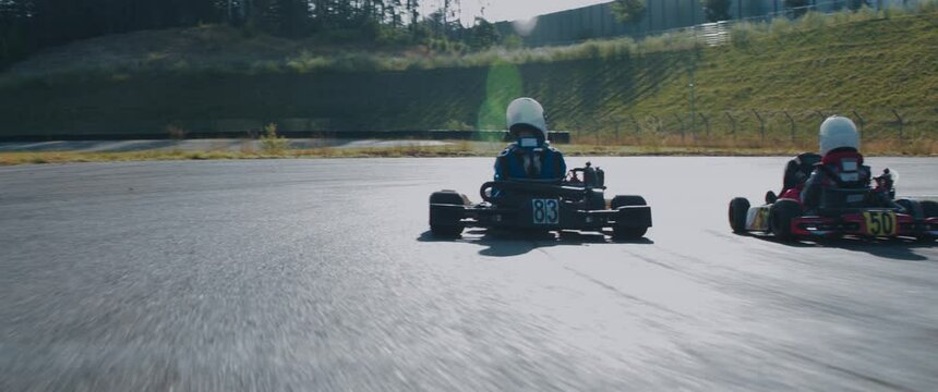 TRACKING Two teenagers pro racers driving their karts on a race track. Shot with 2x anamorphic lens