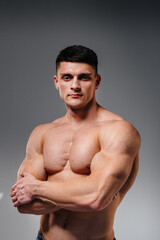 Fototapeta premium A young sexy athlete with perfect abs poses in the studio topless in jeans on the background. Healthy lifestyle, proper nutrition, training programs and nutrition for weight loss.