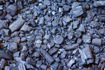 Charcoal for the fire is piled on the ground.