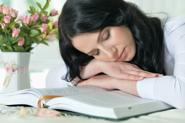 Close up portrait of young woman sleeping on opened big book