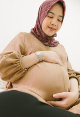Indonesian Muslim woman holding her pregnant belly