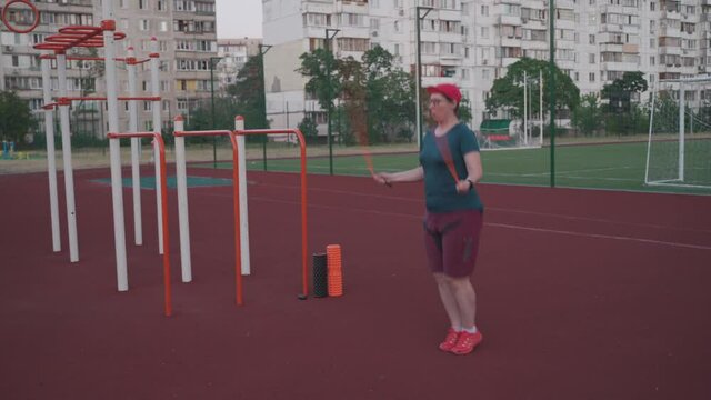 Woman doing jumping rope exercise at the street gym. Fitness workout for weight loss. Cardio load to flush fat. Obese female jumping rope during weight loss. Time to sport. Body positive. Overweight.