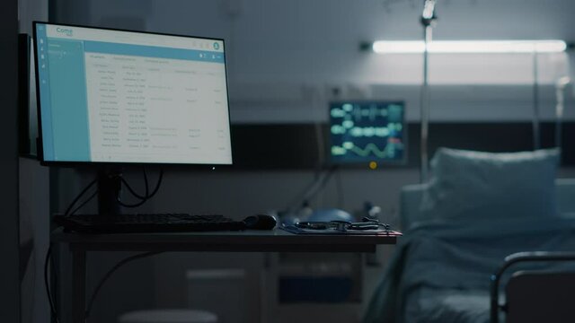 Hospital ward with empty bed and modern equipment at medical facility unit. Nobody in emergency room with files information computer, heart rate monitor, stethoscope and technology