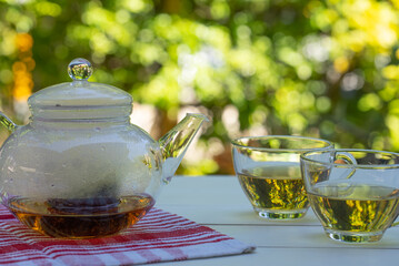 teapot and cups of green and chinese tea on white table in garden