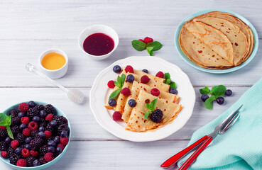 Crepes with berries, breakfast, selective focus, on a white wooden table, horizontal, no people,