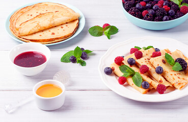Crepes with berries, breakfast, selective focus, on a white wooden table, horizontal, no people,