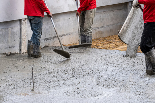 three worker team working wet cement  on floor by use trowel with long Tools spreading poured concrete  on golden sand for strong street after dry.