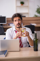 Young alcohol addicted male employee in time management concept