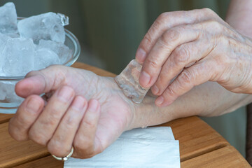 Senior woman holds ice cube on her wrist. How to stay cool in hot weather.