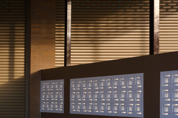 Sunlight and shadow on surface of roller shutter door of commercial buildings separated by a concrete fence in evening time