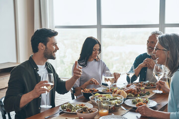 Happy multi-generation family communicating and smiling while having dinner together