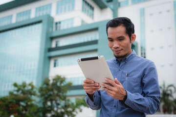 Asian man holding a tablet and looking intently at the screen