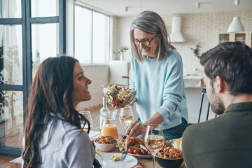 Happy family enjoying delicious dinner and smiling while sitting in the modern apartment
