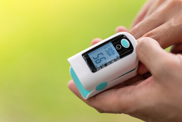 Asian Man measuring oxygen level with modern fingertip pulse oximeter using for measuring heart rate checking oxygen saturation level in the blood diagnosis of Coronavirus or COVID-19 medical concept