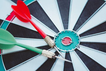 Red and Green dart arrow in on Bullseye target dartboard.