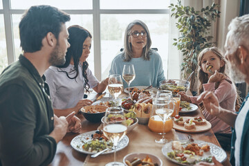 Beautiful multi-generation family communicating and smiling while having dinner together