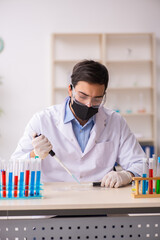 Young male chemist working at the lab during pandemic