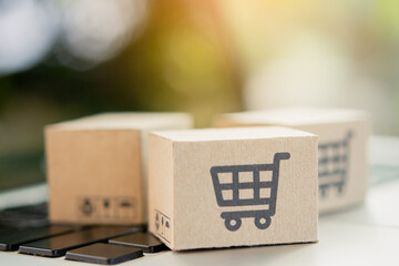 Shopping online. Cardboard box with a shopping cart logo on laptop keyboard. Shopping service on...