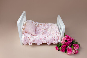 Fototapeta na wymiar baby cot for a photo shoot of newborns. props for a photo shoot. the bed is decorated with pink roses. furniture for dolls