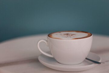 Latte art hot coffee in the morning at a cafe with vintage light as blue background.
