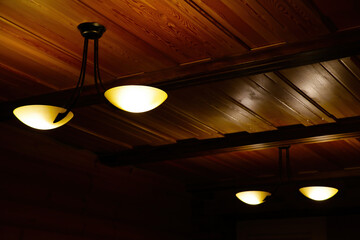 There are lamps on the wooden ceiling.