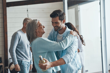 Happy senior parents meeting young couple inside the house