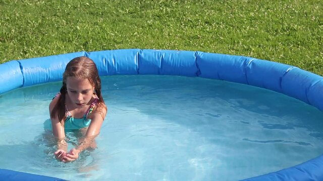 Natural lighting. bright sun. A girl in a swimsuit is swimming in a small pool. Close-up.