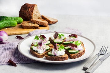 Canapes with toasted bread with sunflower and flax seeds, feta cheese, cucumber and onion