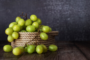 a bunch of grapes in a basket made of jute thread on a dark background horizontal orientation