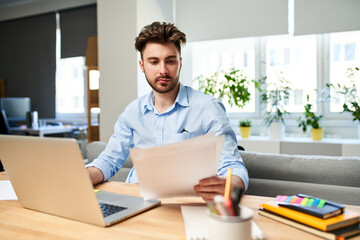 Young man browsing documents while working from home office - obrazy, fototapety, plakaty