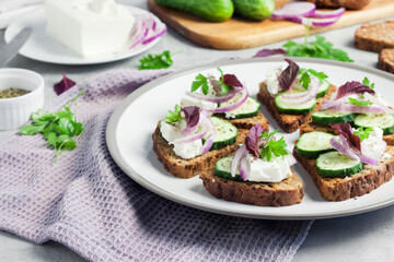 Canapes with toasted bread with sunflower and flax seeds, feta cheese, cucumber and onion
