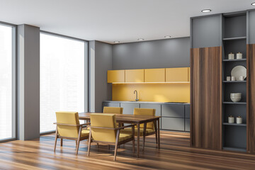 Corner of yellow, grey kitchen area with table, armchairs, panoramic windows