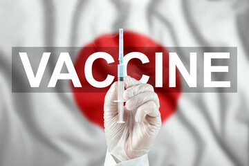 A syringe with a vaccine in the doctor's hand against the background of the flag of Japan. COVID-19 corona virus, immune protection, treatment against nCoV infection 2019, vaccination.
