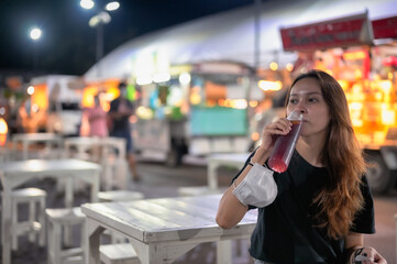Young women  sitting in night market and drinking mineral water , chiang mai north of thailand