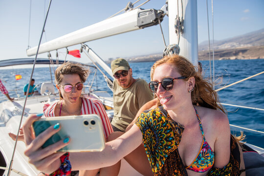 a group of friends, two females and one male, take a selfie during a boat party, happy people during a summer day enjoy life, togetherness concept