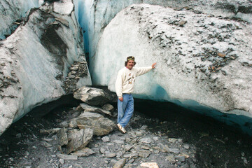 Man Standing Next to a Glacier at the Terminus showing the Scale of the Ice Near Valdez Alaska