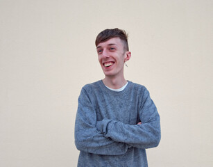 A smiling Caucasian male from Spain standing with arms folded on a plain background