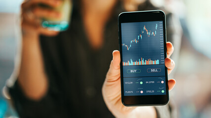 Woman using mobile phone investing application. Stock market investment app in hand. Screen showing close-up