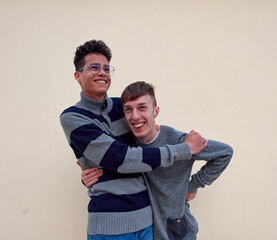 A young interracial gay couple happily hugging isolated on a beige background