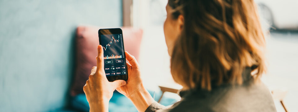 Woman Using Mobile Phone Investing Application. Stock Market Investment App In Hand. Back View