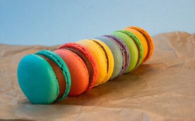 Multicolored macarons with wrapping craft paper on a gray background.